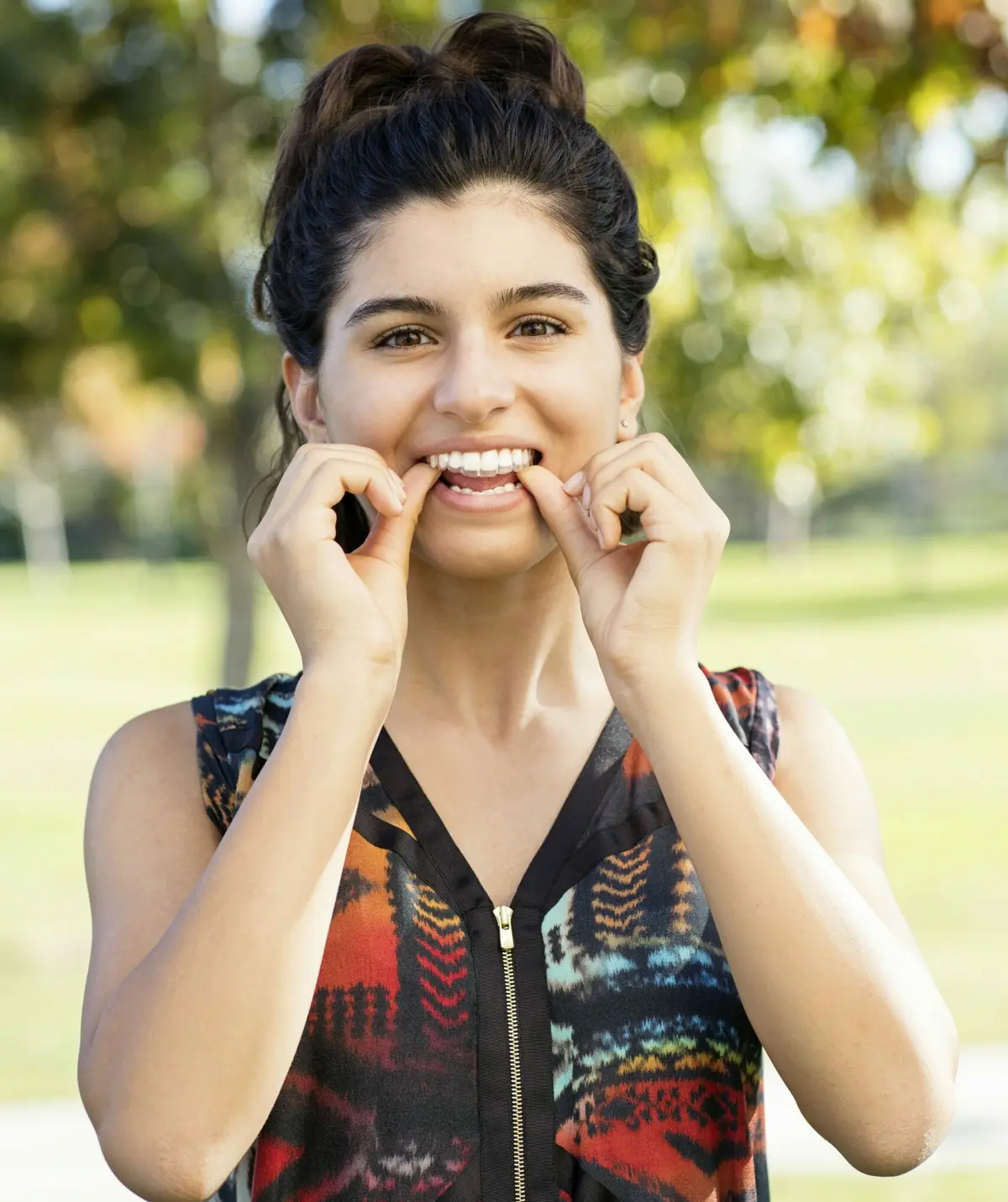 smiling teen placing her invisalign aligners scaled